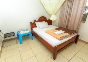 a small bedroom with a bed and a blue table at Admiral Hotel and Spa Kampala in Kampala +25 photos