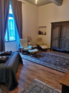 a bedroom with a bed and chairs and a large window at chambres d'hôtes l'atrium in Orange