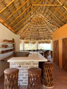 an open kitchen with a large table and stools at Las Casitas de La Bahia Calechosa in Emiliano Zapata