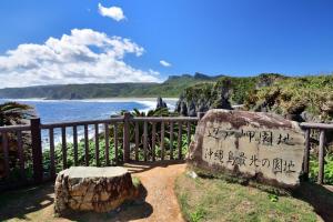 a stone sign with writing on it next to the ocean at Maison Haan Motobu in Motobu