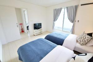a bedroom with two beds and a couch and a tv at Maison Haan Motobu in Motobu