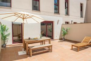 a patio with a table and an umbrella and a bench at The Orbit Apartments in Barcelona