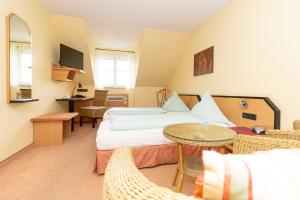 a hotel room with two beds and a table and chairs at Hotel Karger in Wadersloh