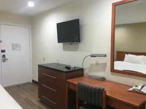 a hotel room with a desk with a bed and a mirror at Simply Home Inn & Suites - Riverside in Riverside