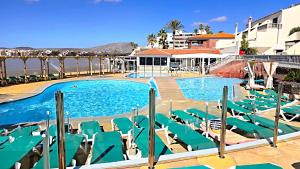a swimming pool with lounge chairs and the ocean at Bellavista Basement in Costa Del Silencio