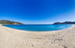 an empty beach with blue water and mountains in the background at Residenza Colombi Goelba in Marina di Campo