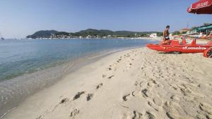 a man standing on a beach with a red boat at Residenza Colombi Goelba in Marina di Campo