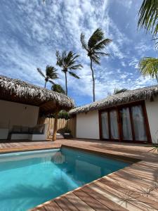 a villa with a swimming pool and palm trees at Tiki Pool's Bungalows in Fortim