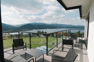 a balcony with chairs and a view of a lake at VILLA nad JEZIOREM in Mucharz