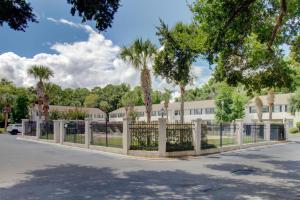 a fence with palm trees in front of a building at Villa Leo in Saint Simons Island