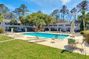 a swimming pool with chairs and a building at Villa Leo in Saint Simons Island