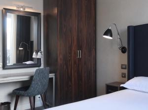 a bedroom with a bed and a mirror and a chair at Hôtel Londres et New York - Teritoria in Paris