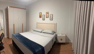 a bedroom with a large bed with white sheets at Dias Felizes - Apto Centro Serra Negra - Edifício Cisne in Serra Negra