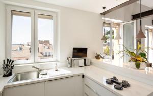 a white kitchen with a sink and two windows at Duplex ForVille in Cannes +18 photos