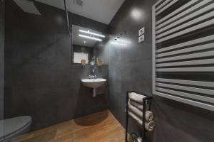 a black bathroom with a sink and a toilet at Apartmán Daniel in Levoča