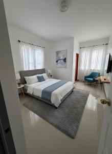 a white bedroom with a bed and a blue chair at La Residencia Homestay in Digos