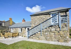 an external view of a stone house with a wooden staircase at 3 Bed in Sennen oc-thbyre in Sennen