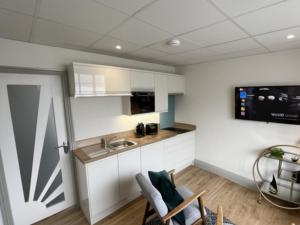 a kitchen with white cabinets and a sink at Sunray Suites in Barmouth