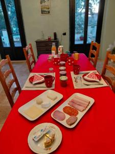 a red table with food and plates on it at La Résolue chambres d'hôtes in Millas