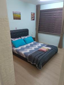 a bedroom with a bed with blue pillows and a window at Kluang Countryside Scenery NO LIFT SECOND FLOOR#NETFLIX#RETRO GAME in Kluang