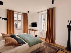 a bedroom with a bed and a tv and windows at MAISON BO TERRA - Chambres et table d'hôtes - Massif des Écrins in Valbonnais