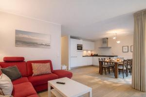 a living room with a red couch and a table at Ferienwohnung Meeresrauschen in Norderney