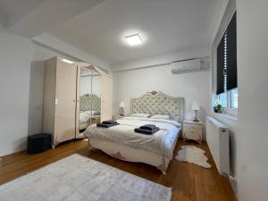 a white bedroom with a large bed and a mirror at Scandinavian AP in Craiova