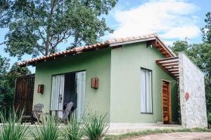 a small green house with two chairs in front of it at Pousada do Dione in Delfinópolis