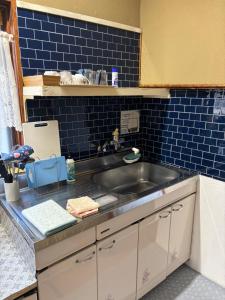 a kitchen with a sink and a blue tiled wall at ゲストハウス樹 in Shingū +57 photos