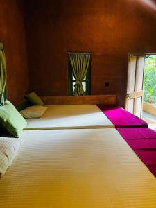 a large bed with colorful sheets on it in a room at Niwana Resort in Ratnapura
