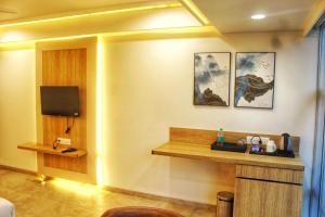 a hotel room with a desk and a tv at All seasons boutique rooms in Pune