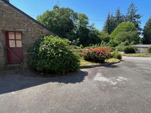 a building with a red door and some flowers at Gîte du Dolmen in Guiscriff