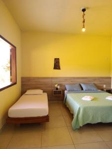 a bedroom with two beds and a yellow wall at Pousada Chales da Canastra in Vargem Bonita +60 photos