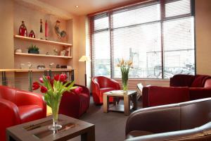 a living room with red chairs and vases of flowers at Hôtel Londres et New York - Teritoria in Paris