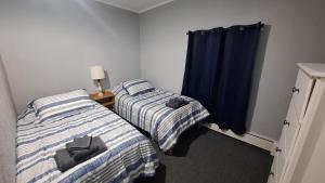 two beds in a room with blue curtains at Oswego 2BR Ground-Floor Apt Near SUNY, Walk to Downtown & Lake Ontario in Oswego