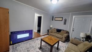 a living room with a tv and a couch and a table at Oswego 2BR Ground-Floor Apt Near SUNY, Walk to Downtown & Lake Ontario in Oswego