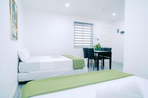 a white room with two beds and a table and a chair at Green Lodging House in Anda