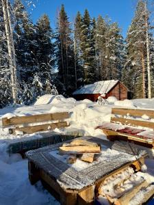 a picnic table in the snow in front of a cabin at Snöbergets Arctic Cabin in Luleå