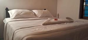 a white bed with white pillows and a stuffed animal on it at Pasikuda Shalom Beach Villa in Kalkudah