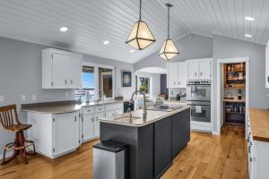 a kitchen with white cabinets and a large island at Shaws Cove Beachouse in Gig Harbor
