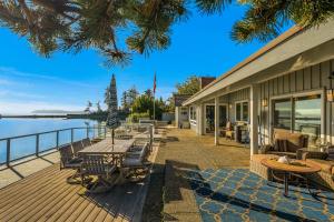 a deck with tables and chairs and the water at Shaws Cove Beachouse in Gig Harbor