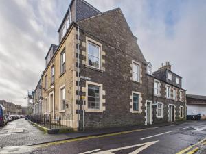 an old brick building on the side of a street at The Bridge View Apartment in Hawick