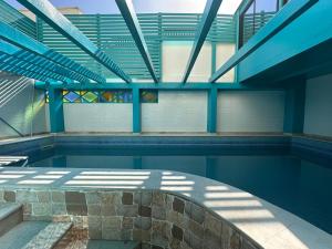 an indoor swimming pool with blue beams and windows at Villa L'initiale in Oualidia