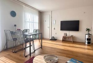 a living room with a table and chairs and a flat screen tv at Stilvolles Wohnen an der Goldküste, nahe Zürich - 55m2 in Erlenbach