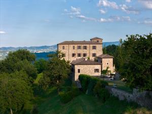 an old stone building on a hill with trees at Castello di Viano in Viano