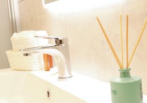 a bathroom sink with a faucet and a vase with sticks at Tower Suite Trento in Trento