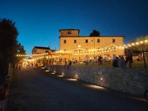 a group of people standing in front of a building with lights at BORGO A MONTI di Sotto in Gaiole in Chianti +94 photos