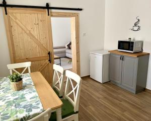 a room with a table and a door with a microwave at Fenyőudvar Vendégház Mocsa in Mocsa