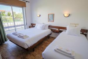 a hotel room with two beds and a window at Residencial Campo-Mar by Umbral in Portimão