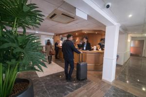 a man standing with a suitcase in an office at Geographotel Paris-Roissy CDG Airport in Le Mesnil-Amelot